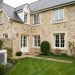 Maison individuelle française en rénovation avec une pompe à chaleur air-eau extérieure discrètement installée dans le jardin.